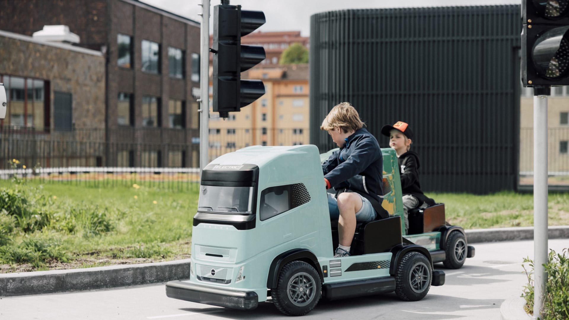 Barn kör eldrivna Volvo-lastbilar i barnstorlek på Traffic School utomhusbana på World of Volvo i Göteborg.