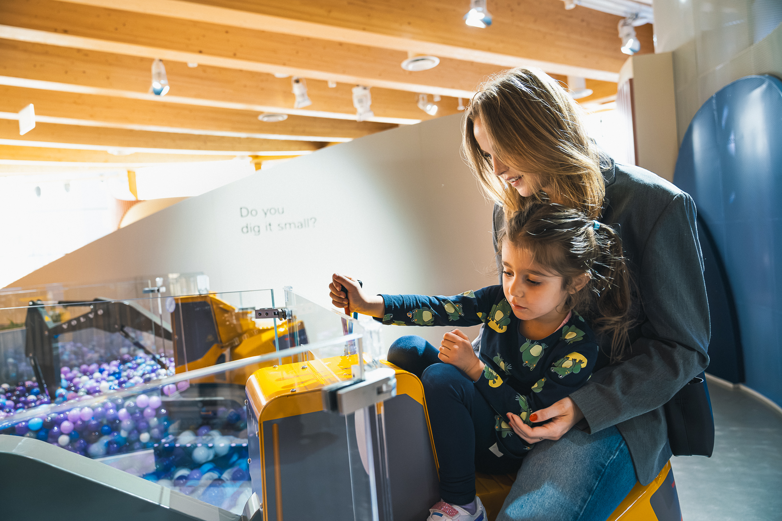 Visitor and child operating a mini excavator in the ”World of Volvo Exhibition” at World of Volvo in Gothenburg.