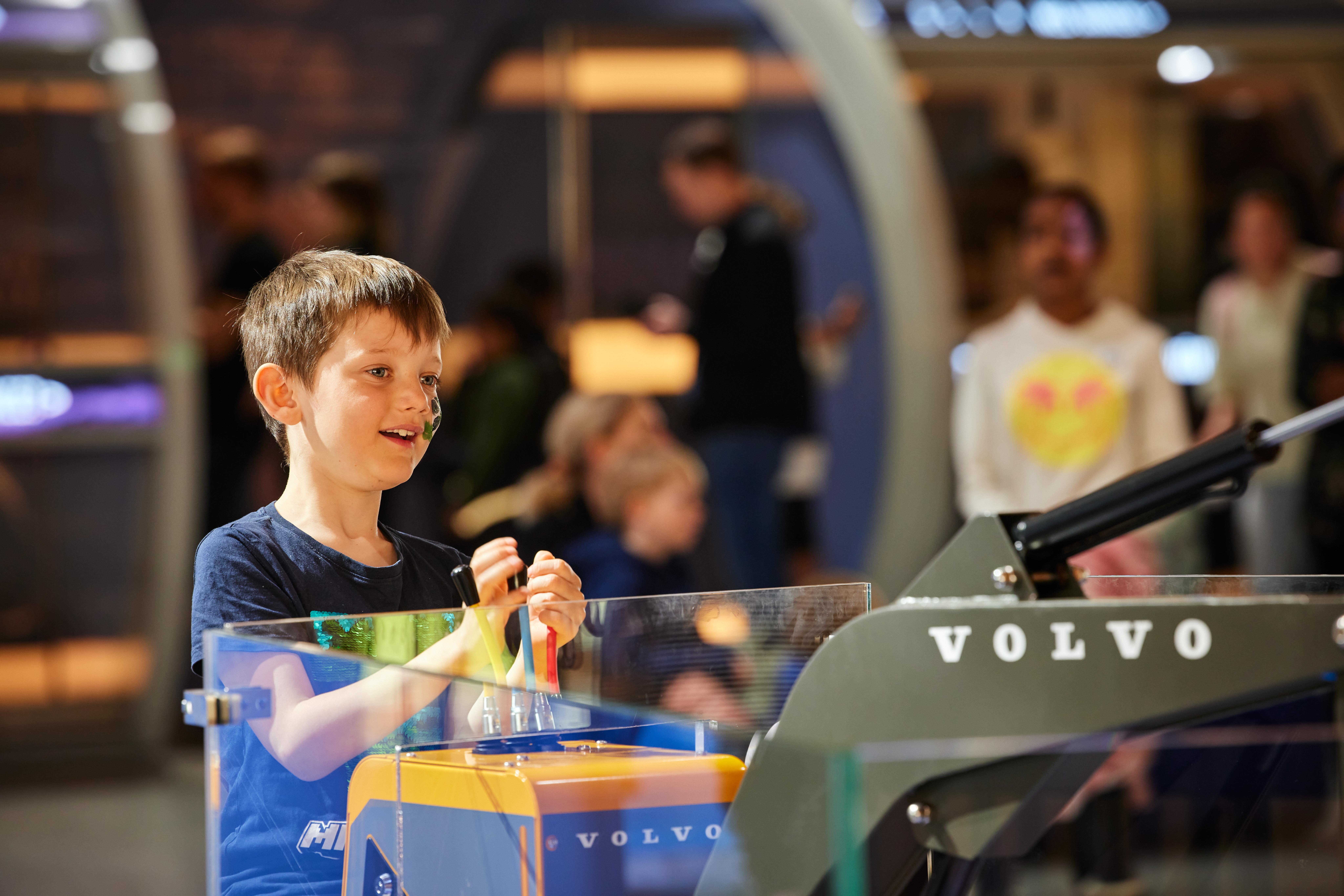Child operating a mini excavator in the ”World of Volvo Exhibition” at World of Volvo in Gothenburg.